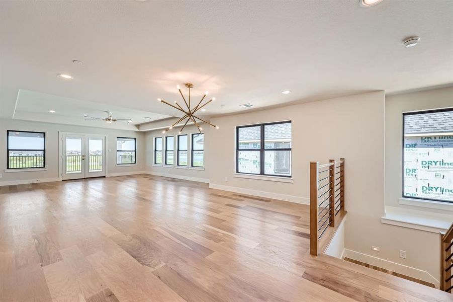 Unfurnished living room with light wood-type flooring and ceiling fan with notable chandelier