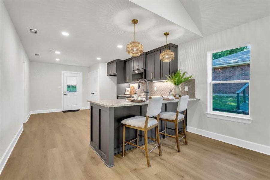 Kitchen with a peninsula, light wood-style flooring, recessed lighting, a kitchen breakfast bar, and backsplash Kitchen with a peninsula, light wood-style flooring, recessed lighting, a kitchen breakfast bar, and backsplash