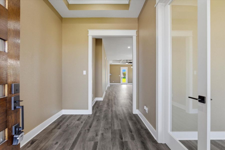 Upon entering the home, you’re welcomed by 10-foot ceilings that elevate into an elegant 11-foot tray ceiling. To the right, the first bedroom offers versatility and can easily serve as a home office.