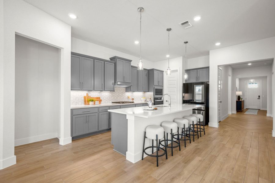 Kitchen featuring a kitchen bar, tasteful backsplash, gray cabinetry, pendant lighting, and recessed lighting