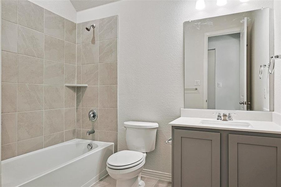 Full bathroom with tiled shower / bath, vanity, toilet, and tile patterned floors