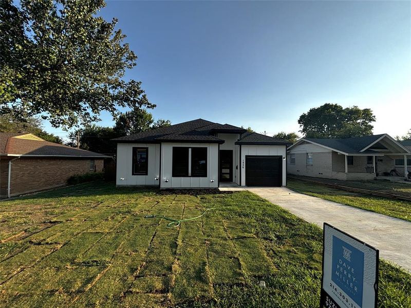 View of front of property featuring a garage and a front yard