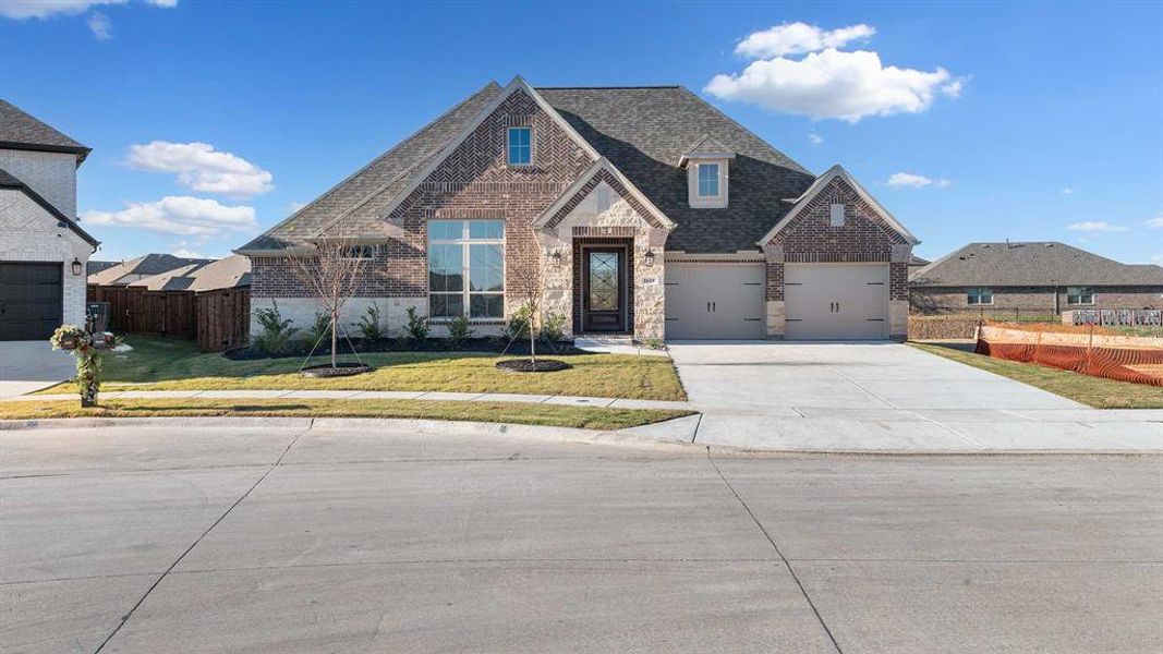 View of front of property featuring a garage and a front lawn