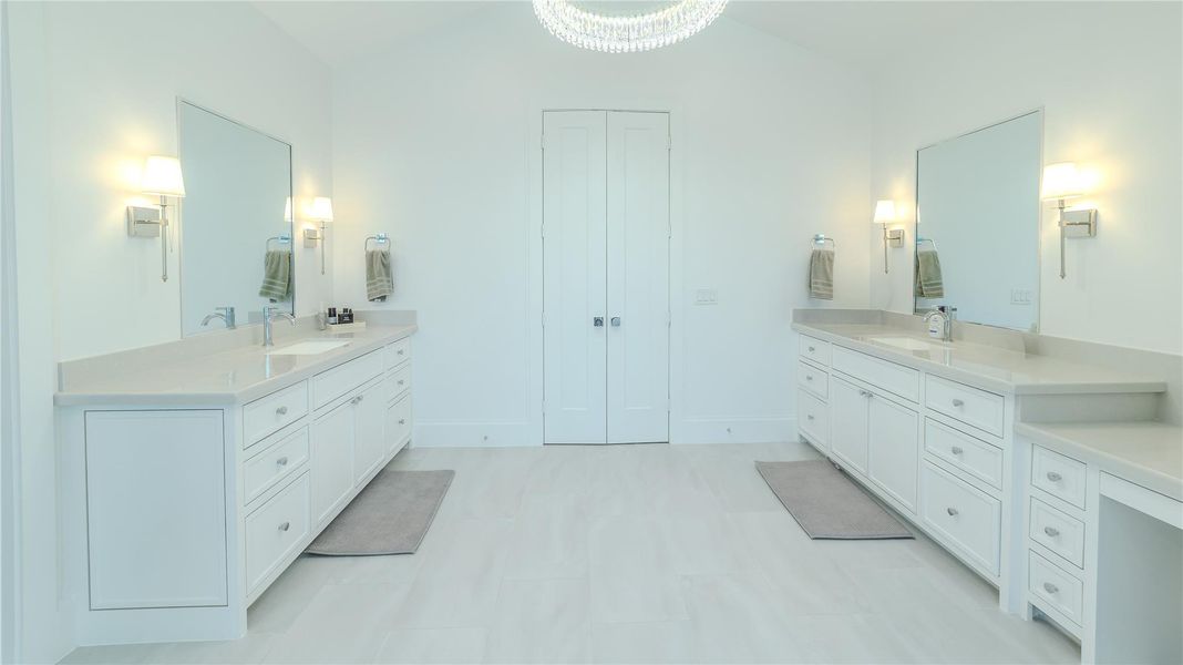 This spacious, bright bathroom features dual vanities with ample storage, large mirrors, and elegant lighting. The sleek, neutral design creates a serene atmosphere ideal for relaxation.