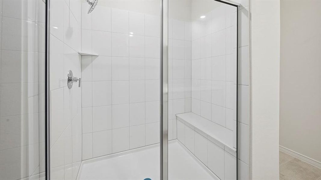 Walk-in shower featuring white subway tile, a built-in bench, recessed niche, chrome fixtures, and a glass enclosure