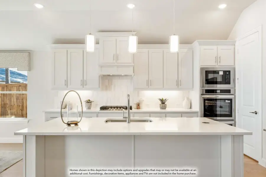 White kitchen with large island, pendant lights, stainless steel appliances, and tile backsplash