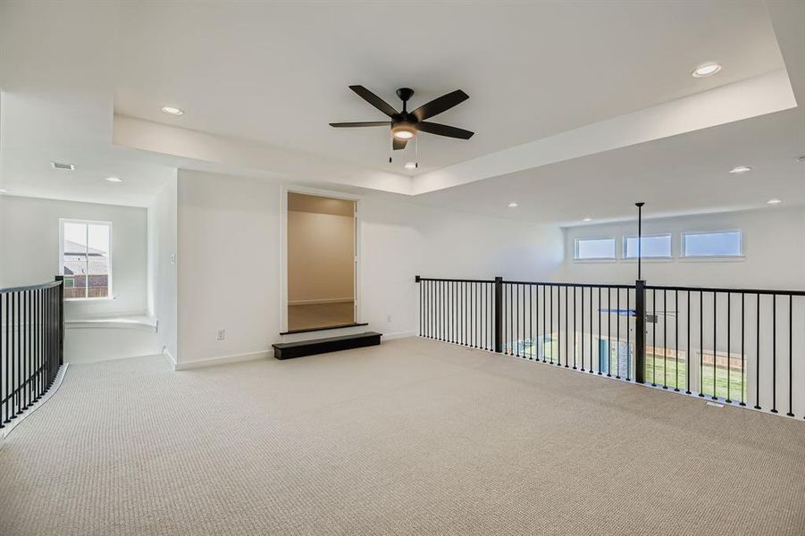 Spare room with a ceiling fan, plenty of natural light, carpet floors, a tray ceiling, and recessed lighting