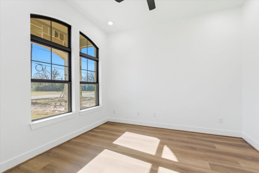 A dedicated first floor office features beautiful forward-facing windows, a ceiling fan, and recessed lighting—ideal for a bright, comfortable workspace.