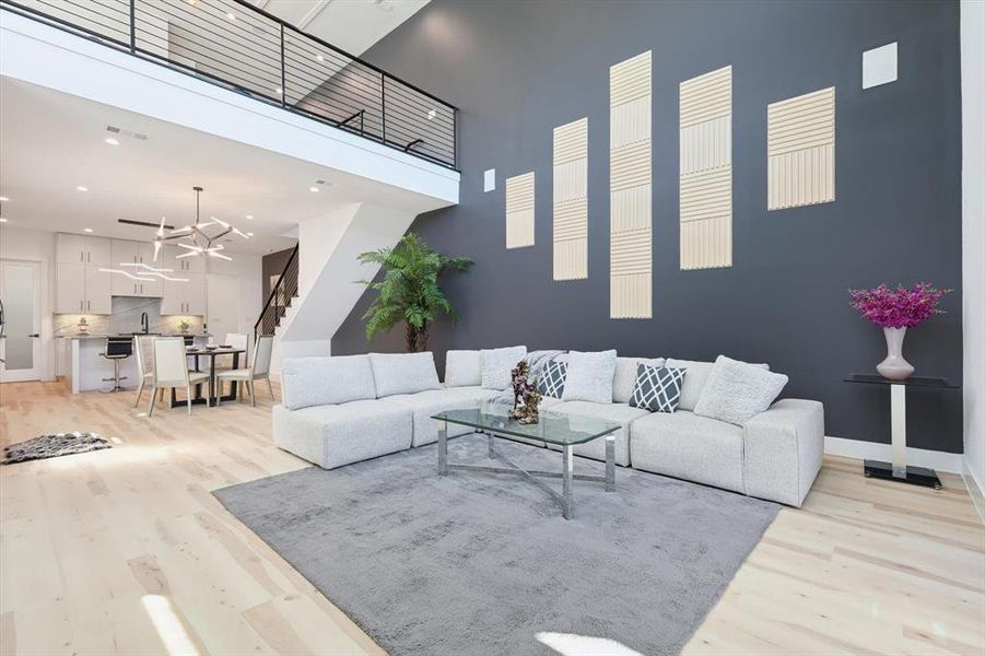 Living room featuring sink, light wood-type flooring, and a towering ceiling