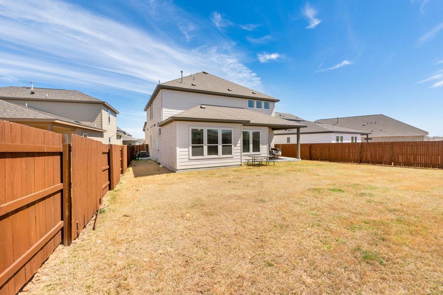 Rear view of property featuring a yard, a patio area, and a fenced backyard