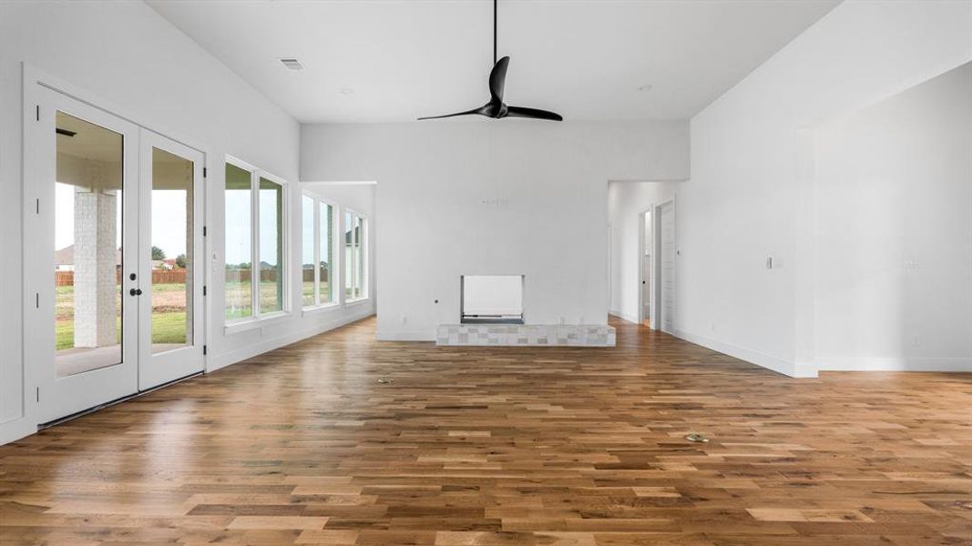 Unfurnished living room with wood-type flooring, ceiling fan, and a tile fireplace