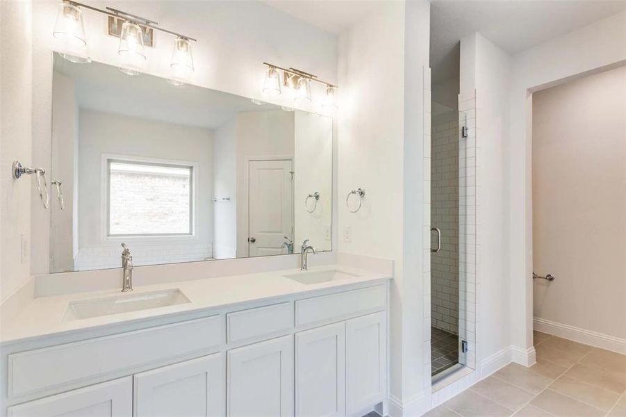 Bathroom with vanity, a shower with shower door, and tile patterned floors