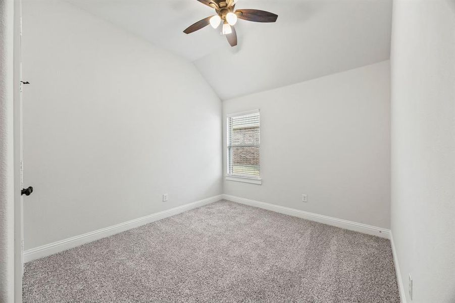 Carpeted empty room with lofted ceiling and ceiling fan