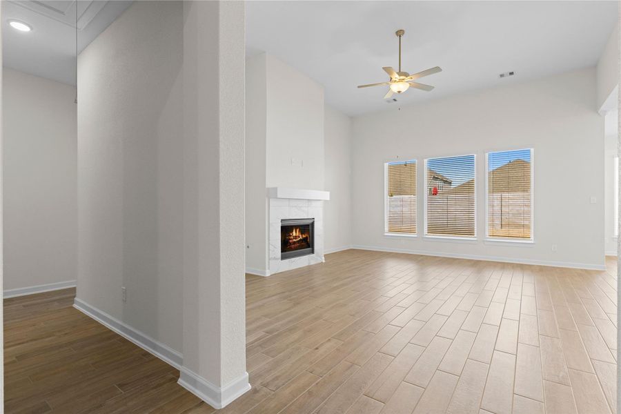 Step into the expansive family room where high ceilings and beautiful wood like tile flooring create an open and welcoming atmosphere, anchored by a cozy gas fireplace that adds charm and comfort for everyday living and special gatherings alike.