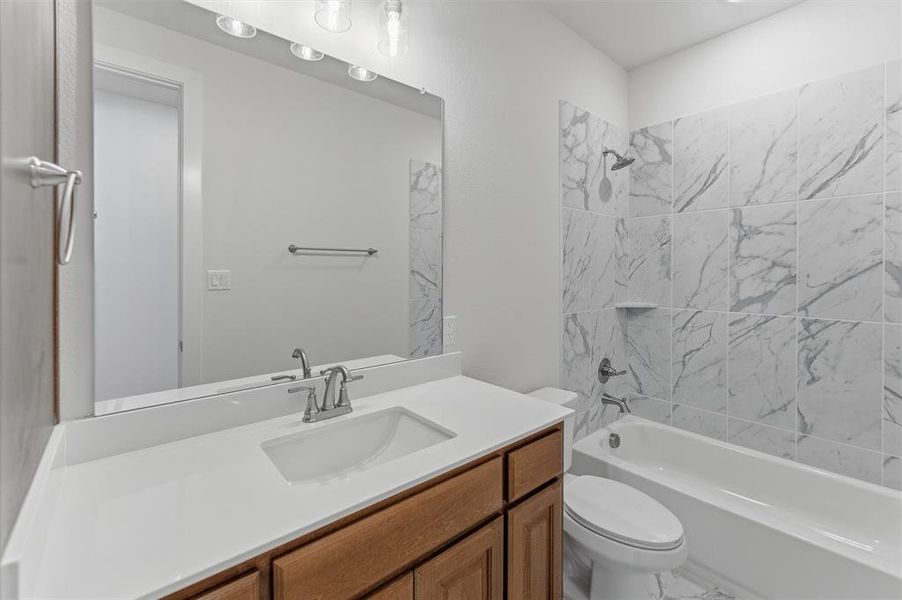 Bathroom featuring a single vanity with wood-finish cabinetry and a white countertop Bathroom featuring a single vanity with wood-finish cabinetry and a white countertop