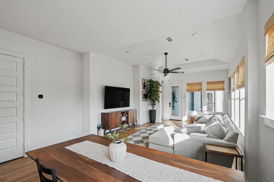 Comfortable living area bathed in natural light, featuring a tray ceiling, wood flooring, and easy access to the outdoor space. The open layout offers a relaxed setting for lounging and casual gatherings.