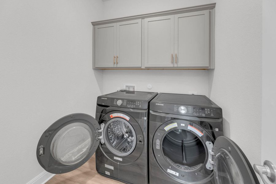 Laundry room featuring wood finished floors, cabinet space, and washing machine and dryer