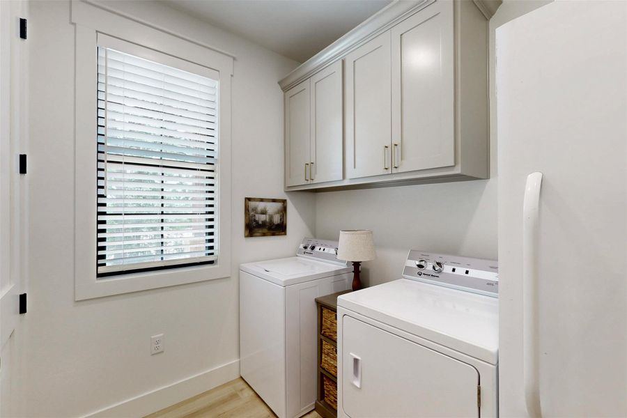 Laundry room featuring washer and clothes dryer, cabinet space, and light wood-style floors