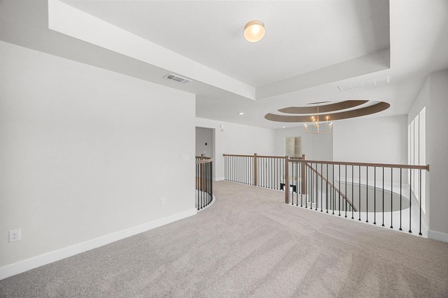 Spare room featuring carpet, a chandelier, and a raised ceiling