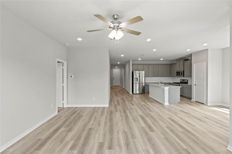 Kitchen with ceiling fan, stainless steel appliances, a kitchen island with sink, light hardwood / wood-style flooring, and gray cabinetry