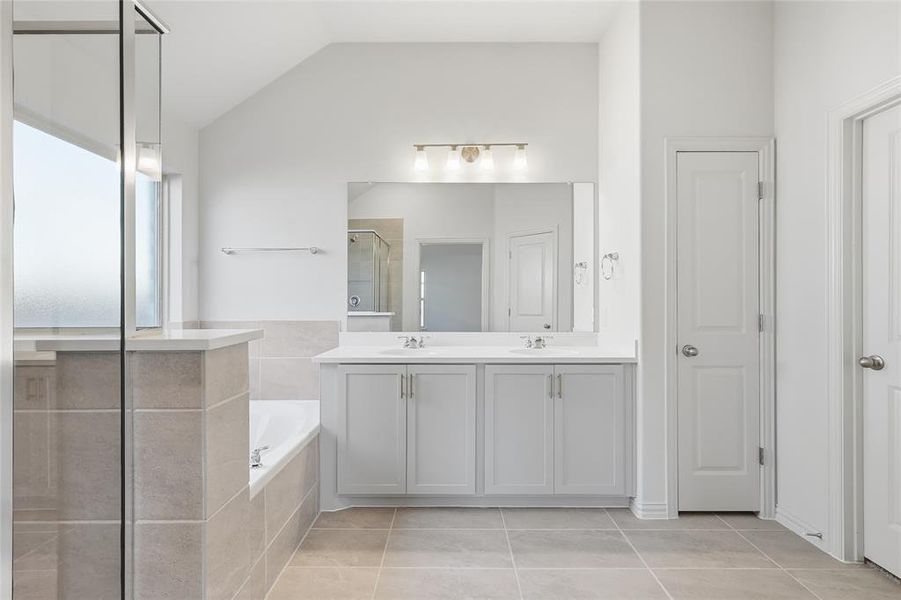 Full bath with a stall shower, double vanity, a bath, light tile patterned flooring, and vaulted ceiling Full bath with a stall shower, double vanity, a bath, light tile patterned flooring, and vaulted ceiling