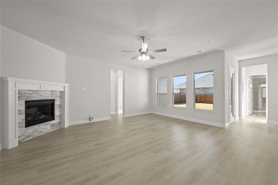 Unfurnished living room featuring ceiling fan, a high end fireplace, and light hardwood / wood-style floors