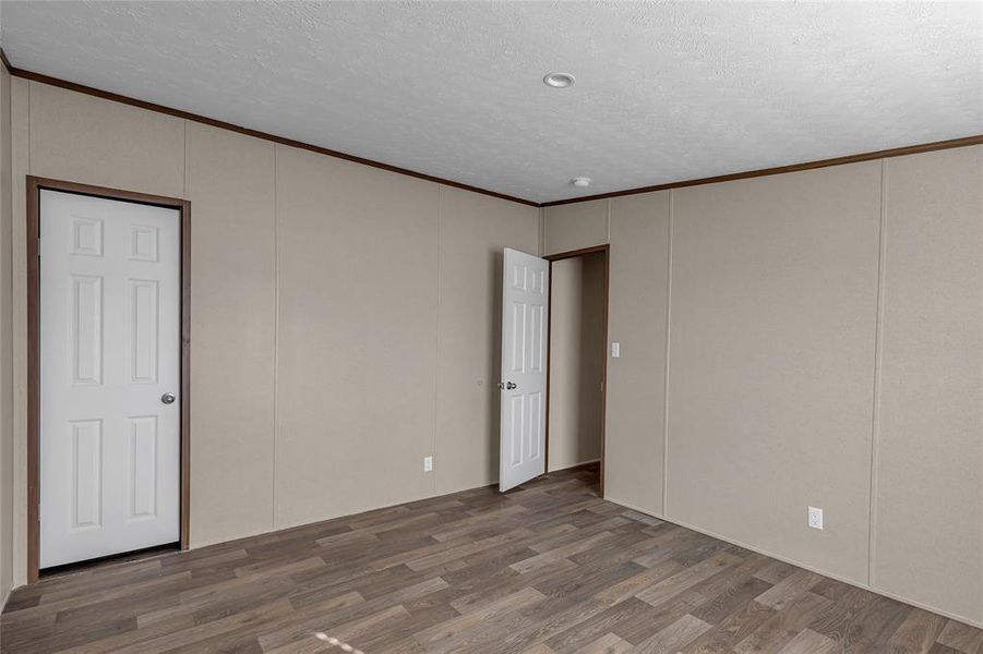 Spare room featuring a textured ceiling, ornamental molding, and dark hardwood / wood-style flooring