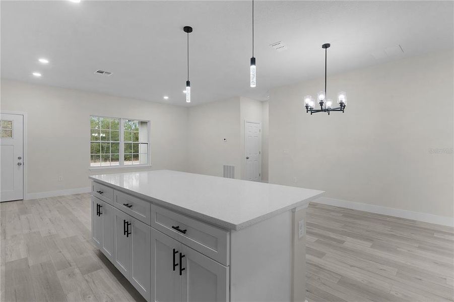 Looking from the kitchen across the island and breakfast bar to the open dining and living areas.