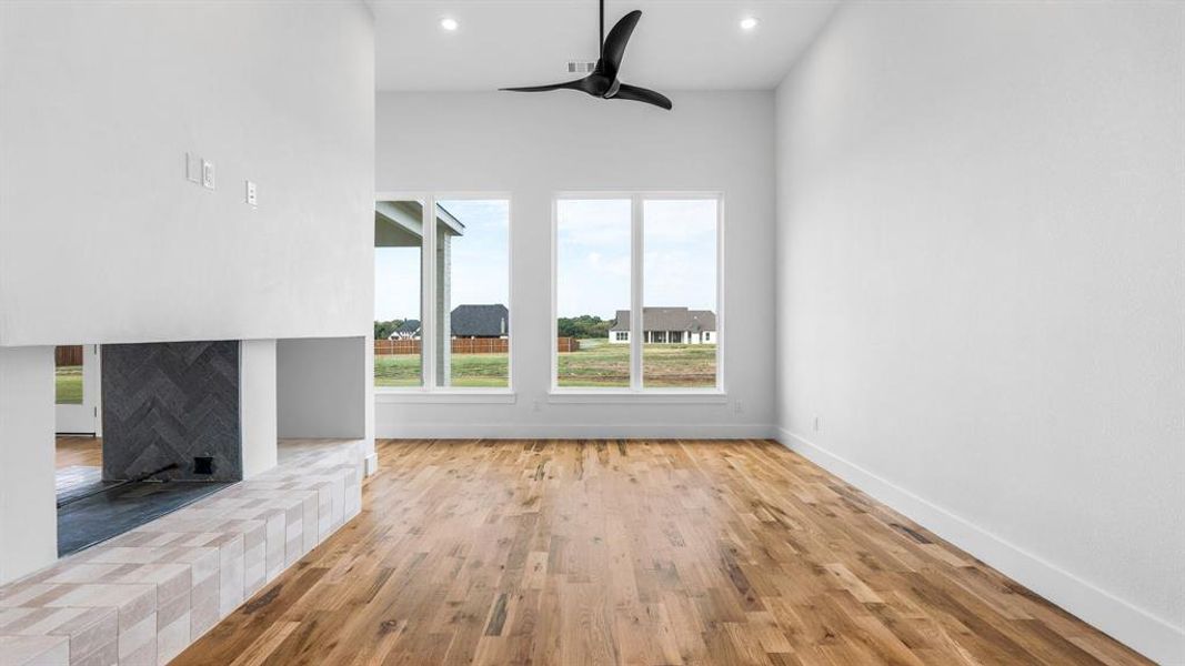 Unfurnished living room with light wood-type flooring, ceiling fan, and a fireplace