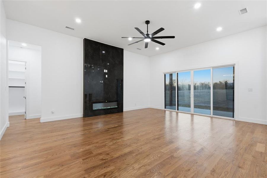 Unfurnished living room featuring ceiling fan, a large fireplace, light wood-type flooring, and recessed lighting