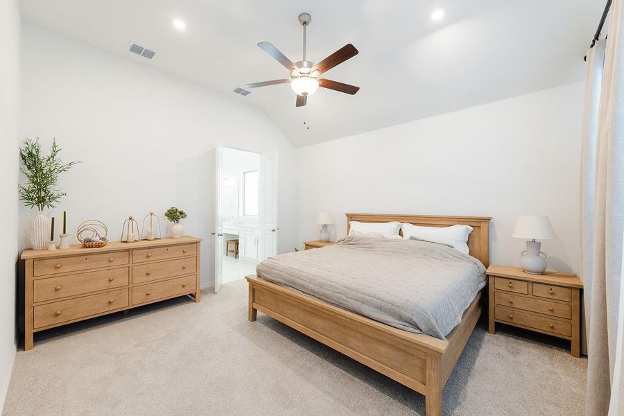Bedroom featuring vaulted ceiling, light colored carpet, ceiling fan, and ensuite bathroom