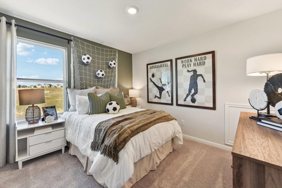 A well-lit bedroom features plush carpeting, recessed lighting, and a window overlooking the neighborhood.
