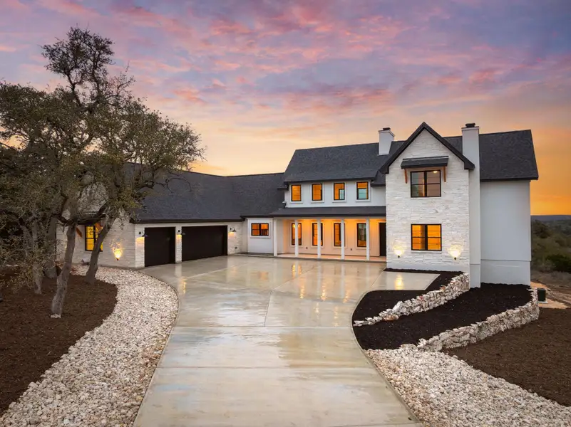 Modern farmhouse style home with an attached garage, a shingled roof, driveway, stone siding, and a chimney