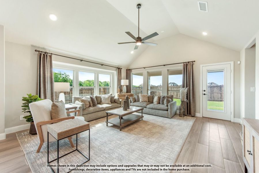 Living room with vaulted ceiling, ceiling fan, hardwood floors, and large windows with backyard views