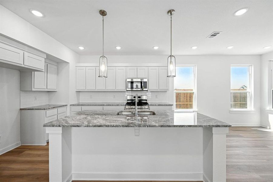 Kitchen featuring dark stone countertops, tasteful backsplash, dark wood-type flooring, white cabinets, and recessed lighting