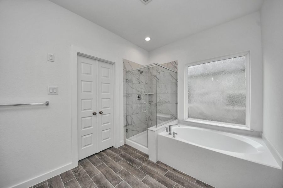 Indulge in a spa-like retreat within the confines of this primary bathroom. Delight in a spacious walk-in shower enveloped in stylish tile surround, unwind in a separate garden tub adorned with custom detailing. Indulge in a spa-like retreat within the confines of this primary bathroom. Delight in a spacious walk-in shower enveloped in stylish tile surround, unwind in a separate garden tub adorned with custom detailing.
