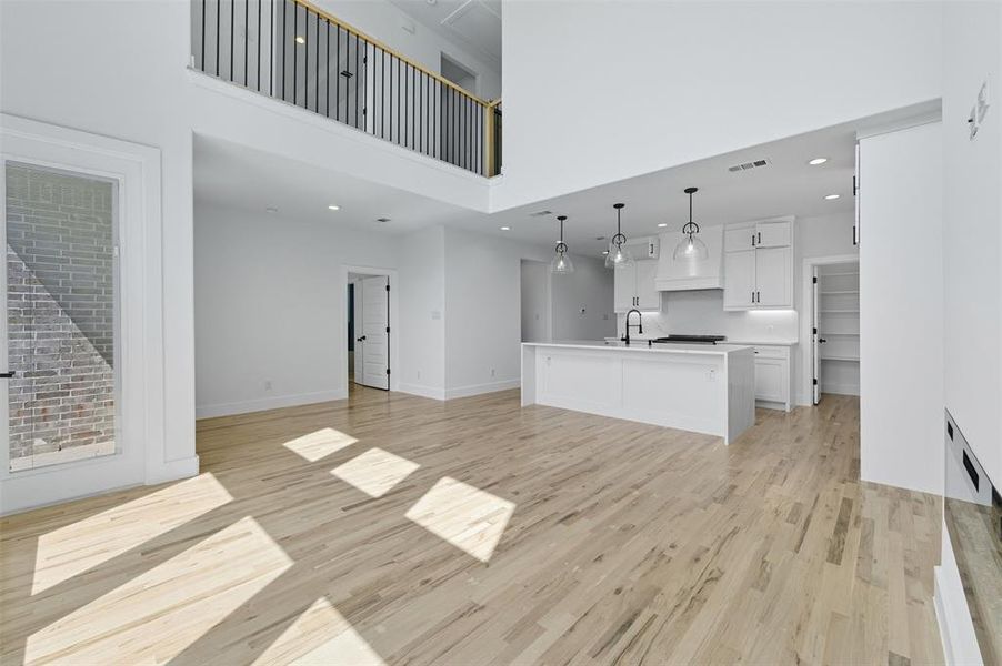 Unfurnished living room featuring light wood finished floors, recessed lighting, and a towering ceiling
