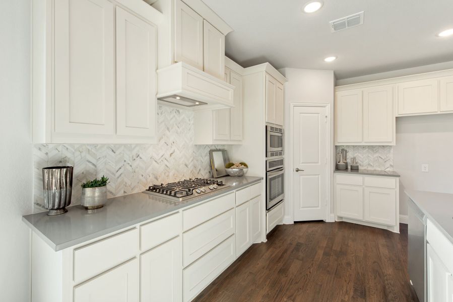 Kitchen with white cabinets, gray countertops, herringbone tile backsplash, gas cooktop, and dark hardwood floors