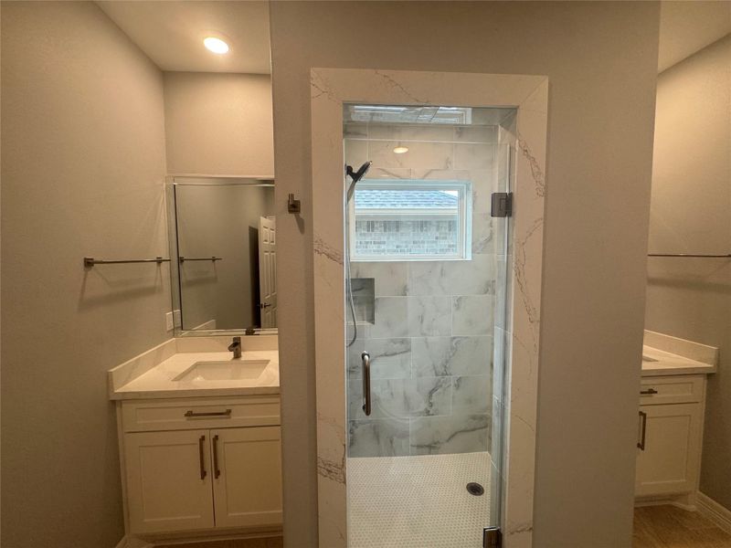 Hall bathroom has 2 vanities with shower in middle