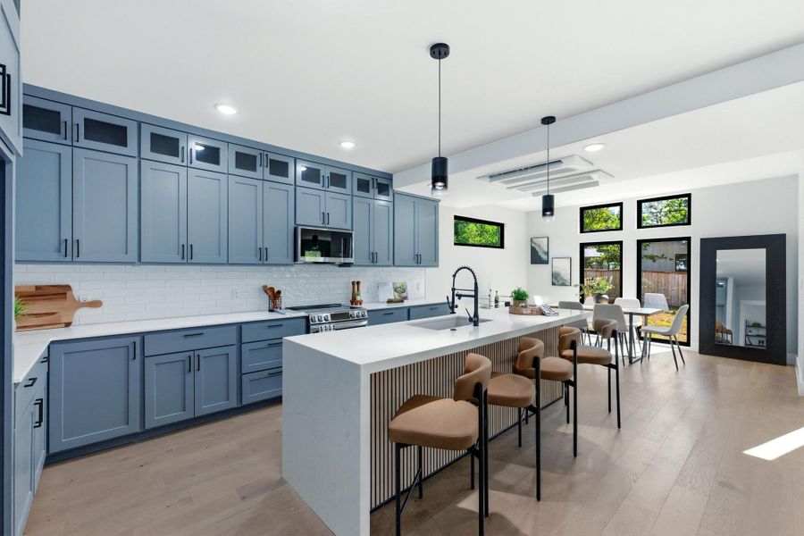 Kitchen with a kitchen bar, light wood-style floors, decorative light fixtures, backsplash, and light stone countertops Kitchen with a kitchen bar, light wood-style floors, decorative light fixtures, backsplash, and light stone countertops