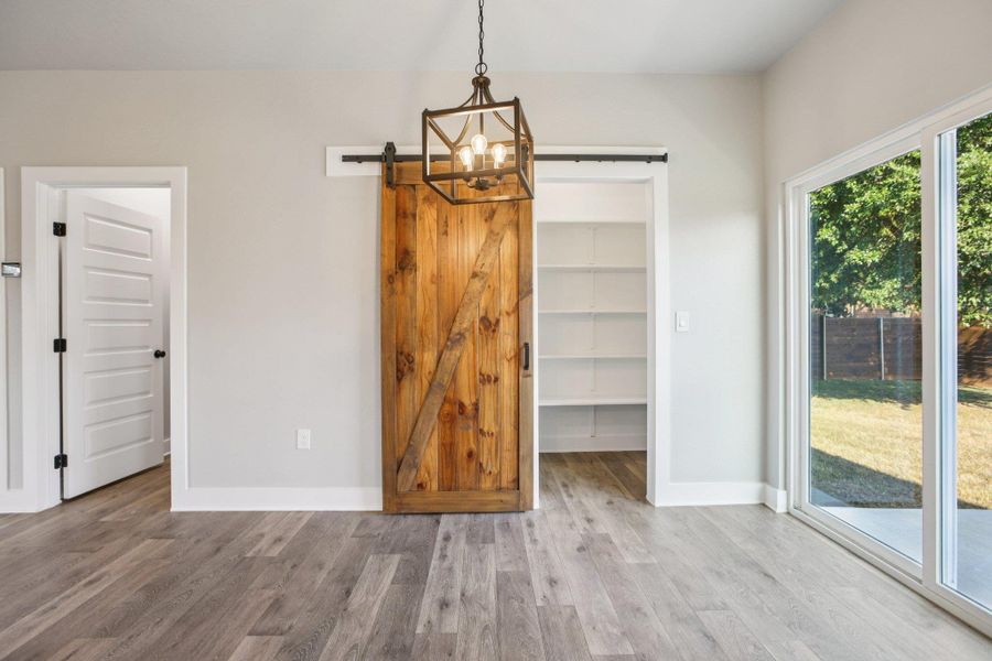 Unfurnished dining area featuring a barn door, wood finished floors, and a chandelier
