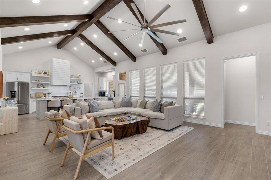 Living area featuring high vaulted ceiling, light wood-style flooring, beam ceiling, recessed lighting, and ceiling fan Living area featuring high vaulted ceiling, light wood-style flooring, beam ceiling, recessed lighting, and ceiling fan