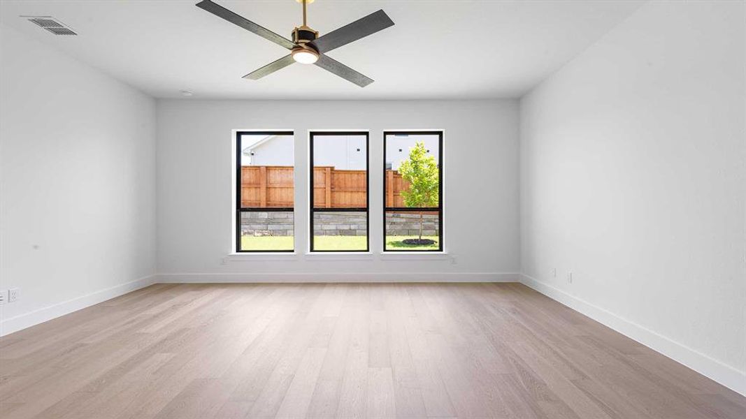 Empty room with healthy amount of natural light, light wood finished floors, and ceiling fan