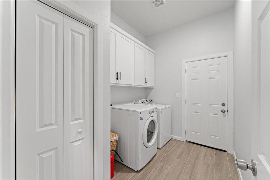 Laundry area with wood finish floors, washer and dryer, and cabinet space