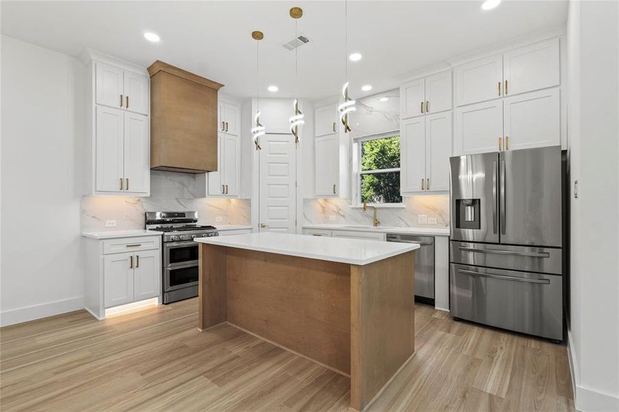 Kitchen with stainless steel appliances, a kitchen island, white cabinetry, pendant lighting, and recessed lighting