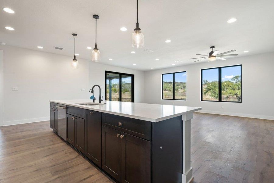Kitchen featuring decorative light fixtures, open floor plan, light wood-style flooring, recessed lighting, and a kitchen island with sink