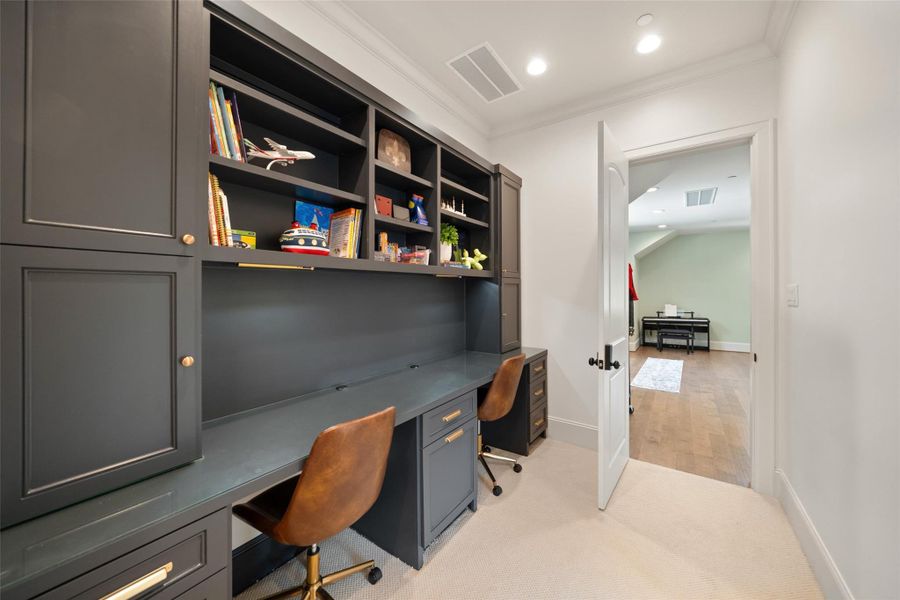 In the hallway, there’s a built-in desk with seating for two, perfect for kids to do homework or for a family member to use as a small office space. It’s a practical and organized nook for daily tasks.