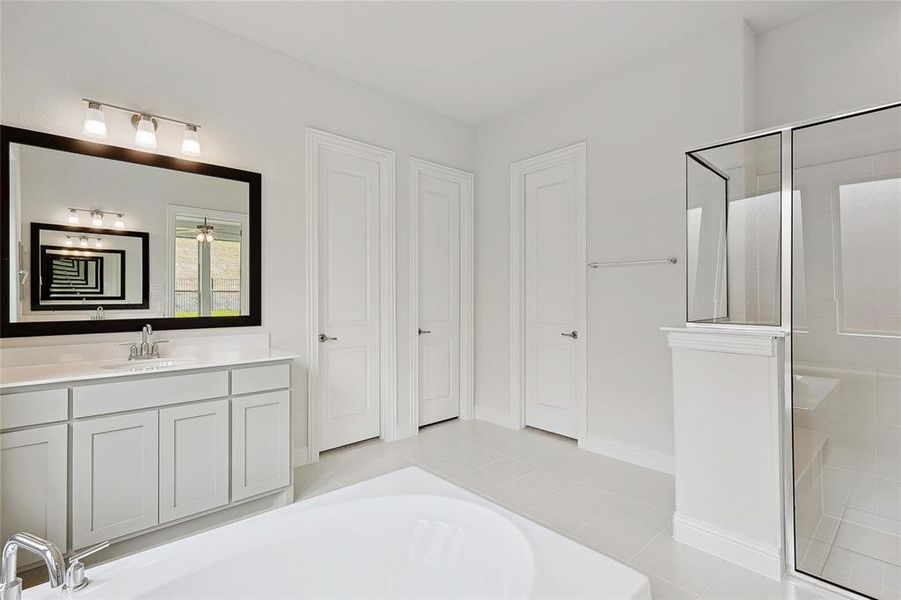 Bathroom featuring vanity, shower with separate bathtub, and tile patterned flooring