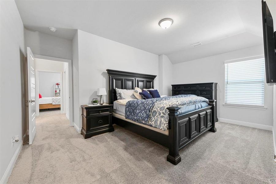 Bedroom with light colored carpet and vaulted ceiling