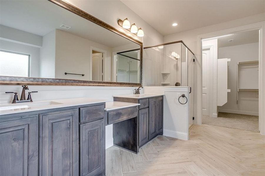 Bathroom featuring a shower with shower door, dual bowl vanity, and parquet flooring